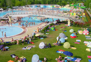 Overfyldt poolområde og grønne områder med farverige parasoller ved Camping Village Marina di Venezia, Italien.