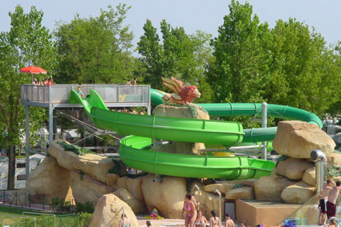 Tobogán acuático verde entre rocas y gente en el Camping Village Marina di Venezia, Veneto, Italia.