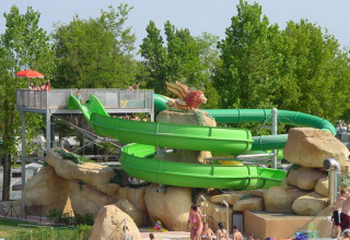 Scivolo d'acqua verde con rocce e persone al Camping Village Marina di Venezia, Veneto, Italia.