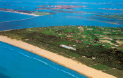 Aerial view of Camping Village Marina di Venezia with lush fields, sandy beach and blue sea in Veneto, Italy.
