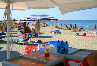Beach view at Camping Village Marina di Venezia in Veneto, Italy, with sunbeds, umbrellas, and visitors.