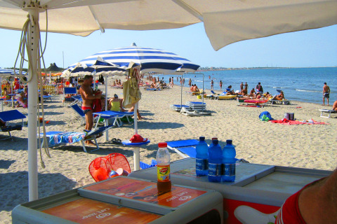 Strand bij Camping Village Marina di Venezia in Veneto, Italië, met ligstoelen, parasols en vakantiegangers.