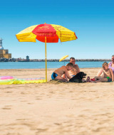 Una familia descansa bajo una sombrilla en la playa en Camping Village Marina di Venezia, Véneto, Italia.