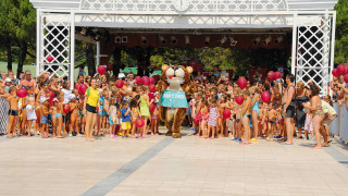 Niños y adultos reunidos alrededor de una mascota con globos en Camping Village Marina di Venezia en Italia.