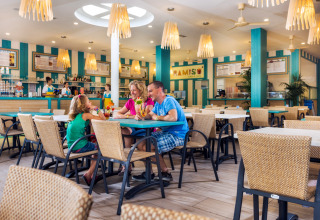 Famiglia che gusta drink colorati al ristorante luminoso del Camping Village Marina di Venezia, Veneto, Italia.