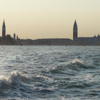 Olas del mar frente al perfil urbano de Cavallino/Treporti con torres en Veneto, Italia, al atardecer.