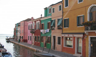 Casas coloridas en un canal de Cavallino/Treporti, Véneto, Italia, con barcos a lo largo del agua.