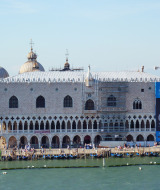 Vista del Palacio Ducal de Venecia con góndolas y turistas bordeando el canal y arquitectura histórica.
