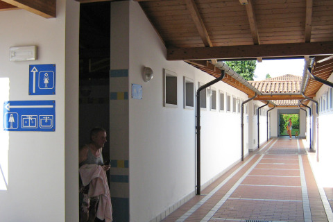 Pasillo con señalización de baños y duchas en Camping Village Marina di Venezia, un parque vacacional en Véneto, Italia.