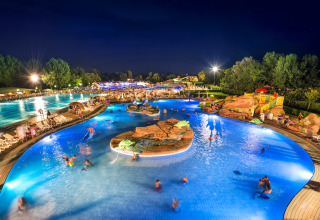 Oplyst swimmingpool ved natten i Camping Village Marina di Venezia, Veneto, Italien, med glade gæster.