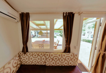 Interior view from SunLodge Maple showing sofa, windows, and door leading to terrace at Camping Village Marina di Venezia.