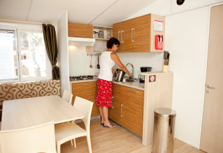 Vrouw doet de afwas in de moderne keuken van SunLodge Redwood, Camping Village Marina di Venezia, Italië.