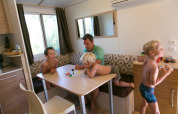Familie speelt een gezelschapsspel in SunLodge Aspen Combi op Camping Village Marina di Venezia, Italië.