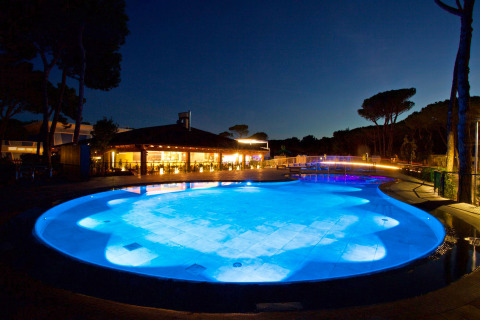 Piscina iluminada por la noche en el camping Village Cavallino, parque vacacional en Véneto, Italia.