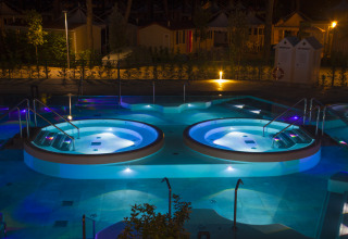 Verlichte jacuzzi’s bij nacht op Camping Village Cavallino, een vakantiepark in Veneto, Italië.