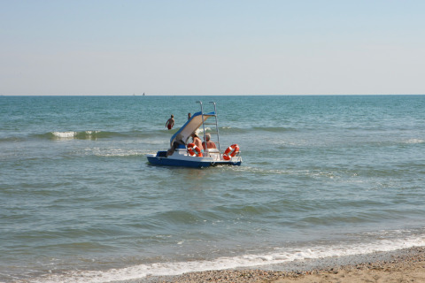 Personas en un bote a pedales con tobogán cerca de la costa en Camping Village Cavallino, Véneto, Italia.