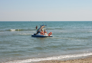 Des personnes sur un pédalo avec toboggan près du rivage au Camping Village Cavallino, Vénétie, Italie.