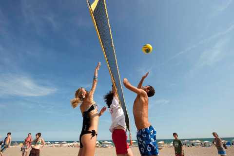 Des jeunes jouent au volley-ball sur la plage au Camping Village Cavallino, sous le ciel bleu, en Vénétie, Italie.