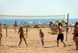 Villeggianti giocano a beach volley sulla sabbia al Camping Village Cavallino in Veneto, Italia.