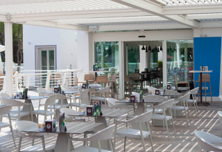 Zona caffè all’aperto con tavoli e sedie bianche moderne al Camping Village Cavallino, Veneto, Italia.