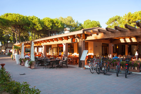 Área de restaurante al aire libre con bicicletas y clientes en Camping Village Cavallino, parque de vacaciones en Veneto, Italia.