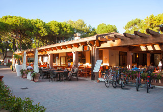 Udendørs restaurantområde med cykler og gæster i Camping Village Cavallino, feriepark i Veneto, Italien.