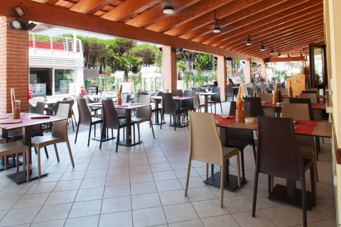Zona de restaurante al aire libre en Camping Village Cavallino, Véneto, Italia, con mesas y sillas vacías.