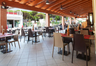 Outdoor dining area at Camping Village Cavallino in Veneto, Italy, featuring empty tables and chairs.