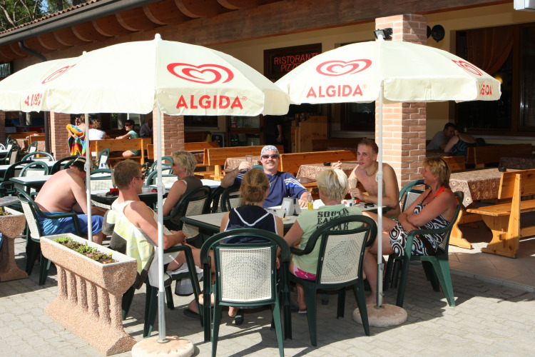 Vakantiegangers genieten van de zon onder Algida-parasols bij Camping Village Cavallino in Veneto, Italië.