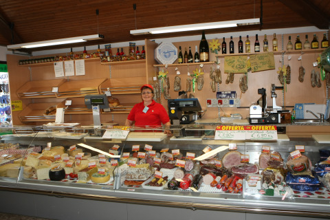 Vrouw achter de toog met kaas en charcuterie in Camping Village Cavallino, Veneto, Italië.