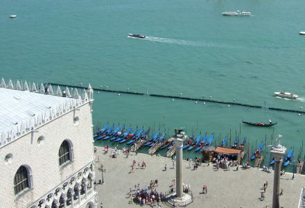 Vista de góndolas atracadas cerca del agua en Cavallino, Véneto, Italia, con gente y arquitectura histórica.