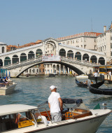 Vista del Gran Canal en Venecia con la famosa Puente de Rialto, botes, góndolas y edificios históricos.