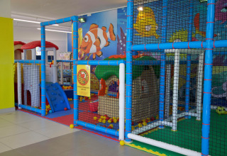 Indoor playground with colorful playhouses and safety nets at Camping Village Cavallino in Veneto, Italy.