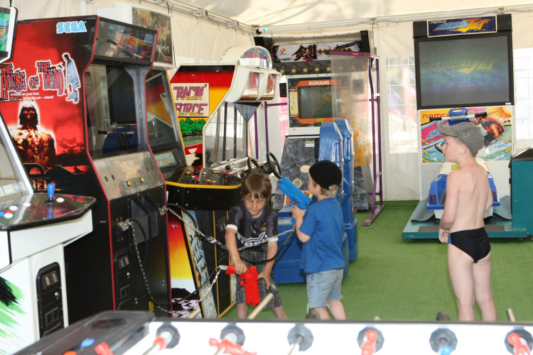 Kinderen spelen op arcadeautomaten in de speelhal van Camping Village Cavallino in Veneto, Italië.