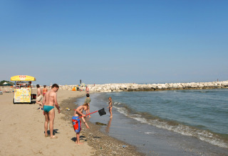 Folk nyder en solrig dag på stranden ved Camping Village Cavallino i Veneto, Italien, nær havet.