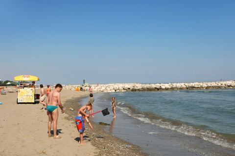 People enjoying a sunny day on the beach at Camping Village Cavallino holiday park in Veneto, Italy.