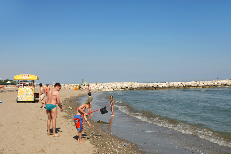 Mensen genieten van een zonnige dag op het strand bij Camping Village Cavallino in Veneto, Italië.