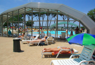 Udendørs poolområde med solstole og folk, der soler sig i hu Park Albatros Village i Toscana, Italien.