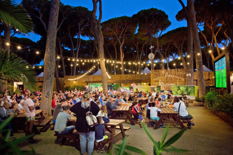 Multitud ve un partido de fútbol en pantalla gigante al aire libre en hu Park Albatros Village, Toscana, Italia.