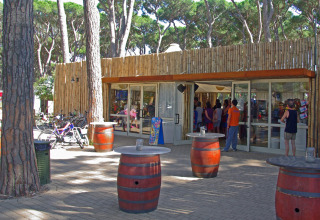 Udendørs caféområde med tøndeborde og gæster foran hu Park Albatros Village i Toscana, Italien.