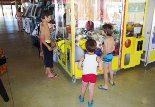 Children play at a claw machine in Hu Park Albatros Village, a holiday park located in Tuscany, Italy.