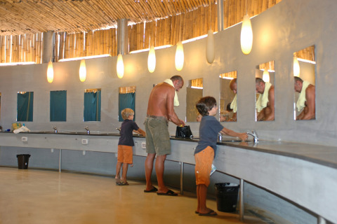 Familia lavándose las manos en el moderno baño común de hu Park Albatros Village, Toscana, Italia.