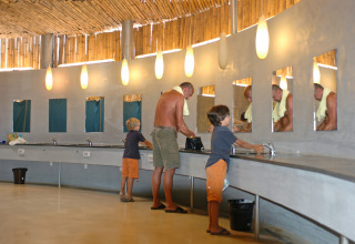 Famiglia che si lava le mani nel moderno bagno comune di hu Park Albatros Village in Toscana, Italia.