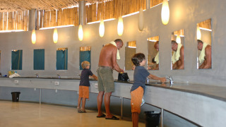 Familia lavándose las manos en el moderno baño común de hu Park Albatros Village, Toscana, Italia.