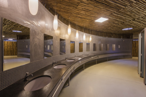 Baño moderno con mostrador curvo y espejos en Park Albatros Village, parque vacacional en Toscana, Italia.