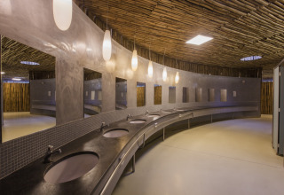 Moderne badeværelsesfaciliteter med buet disk og spejle i Park Albatros Village, Toscana, Italien.
