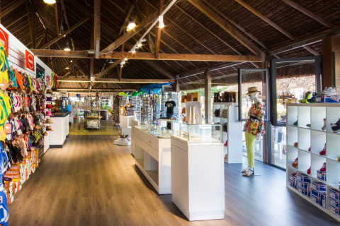 Shop at hu Park Albatros Village in Tuscany, Italy, featuring colorful sandals, bags, and a mannequin display.