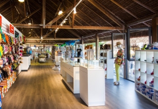 Boutique au hu Park Albatros Village en Toscane, Italie, avec sandales, sacs colorés et mannequin exposé.