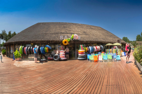 Bazar con salvagenti colorati, sedie da spiaggia e visitatori al hu Park Albatros Village in Toscana, Italia.