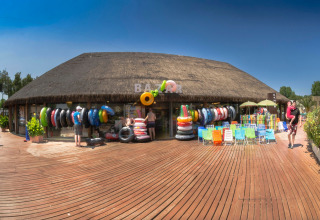 Boutique bazar avec bouées, chaises de plage et visiteurs à hu Park Albatros Village, en Toscane, Italie.